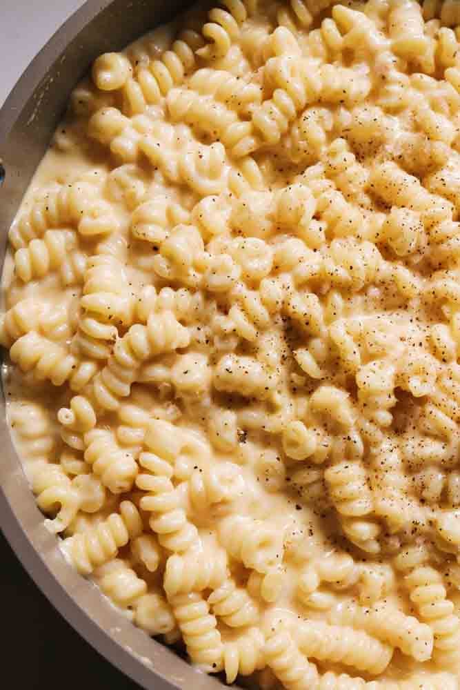 the left side of a pot filled with creamy macaroni and cheese.