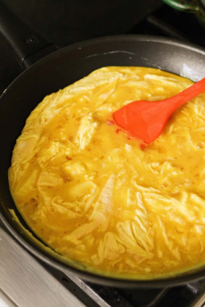 cheesy scrambled eggs in a black nonstick fry pan. 