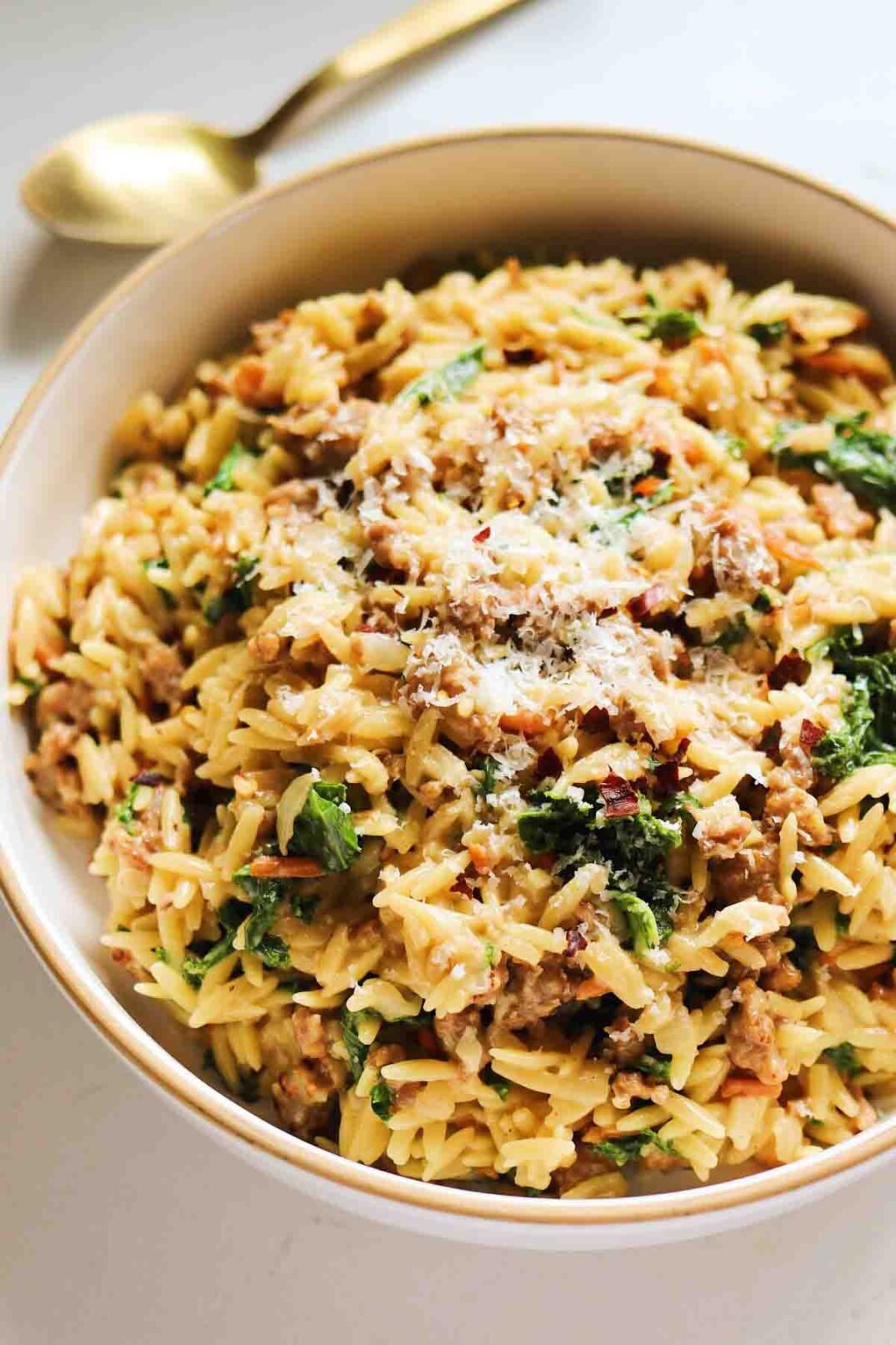 a white bowl full of orzo that's inspired by the flavors of olive garden zuppa toscana. 