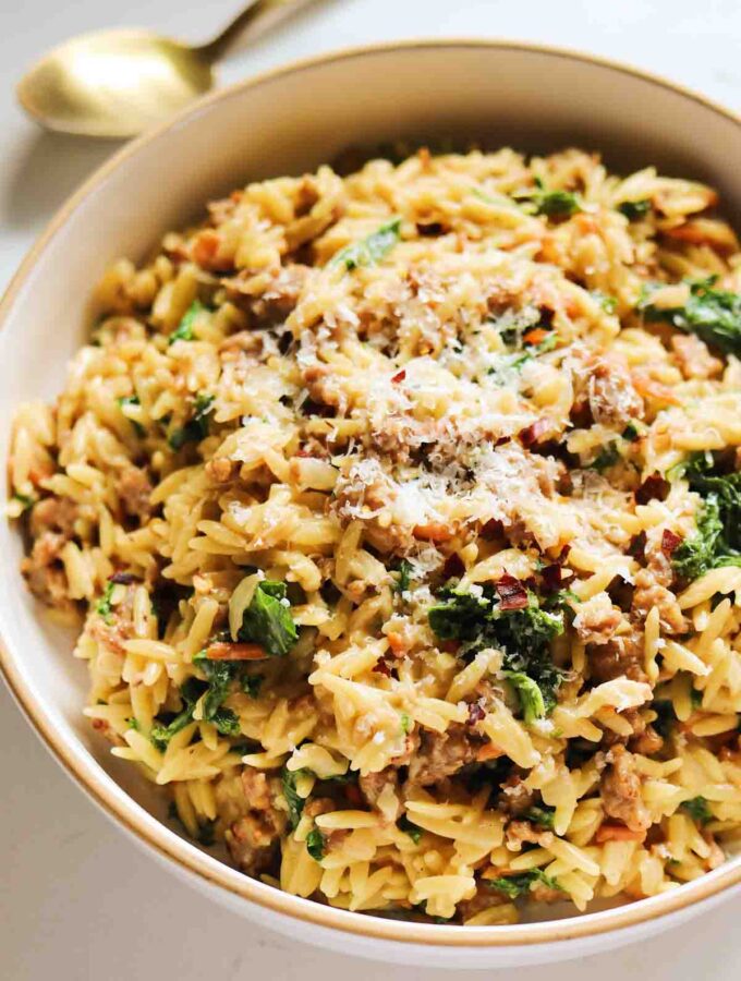 a white bowl full of orzo that's inspired by the flavors of olive garden zuppa toscana.