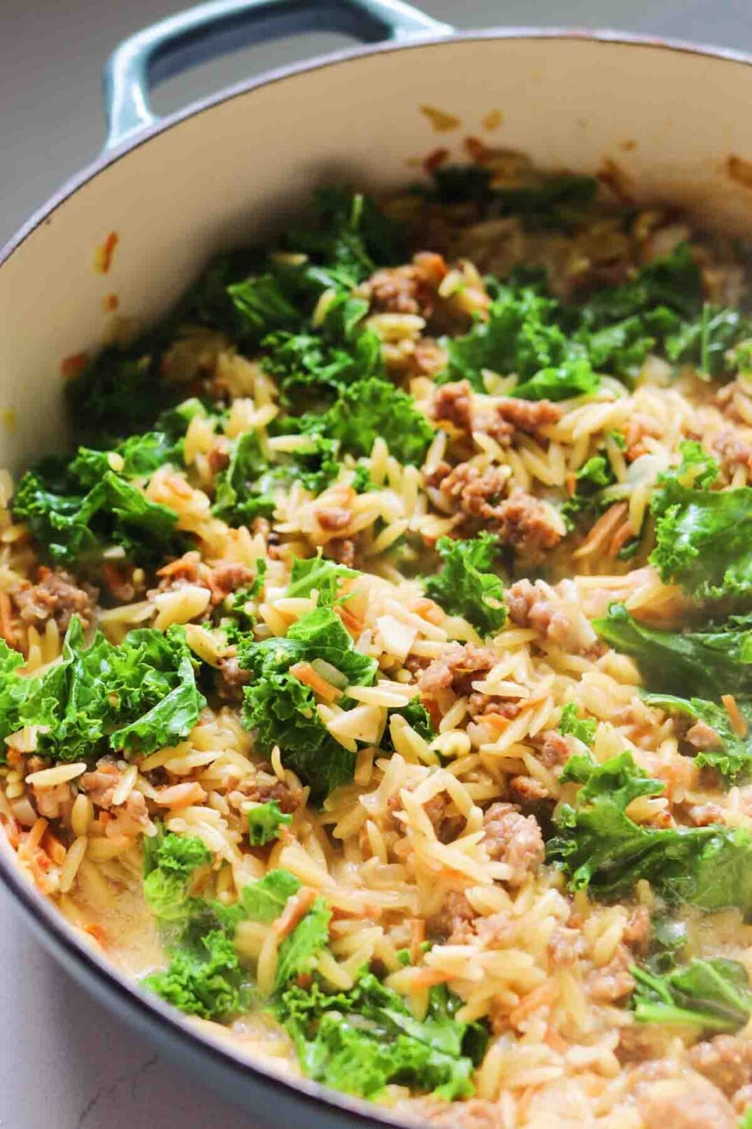 a pot of zuppa toscana flavored orzo topped with fresh kale. 
