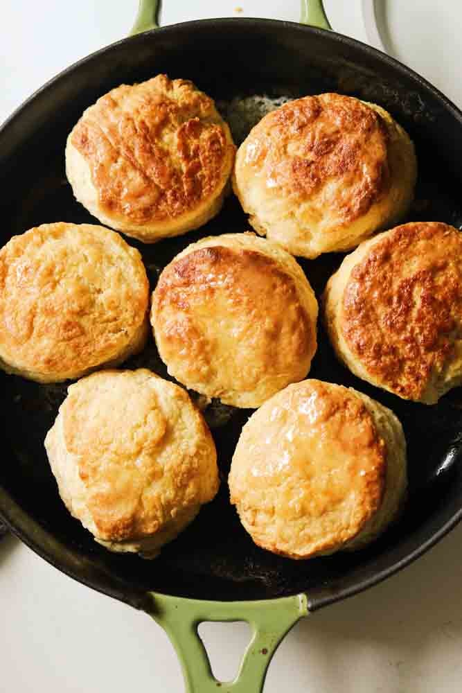 an overhead view of a cast iron skillet filled with honey butter biscuits. 