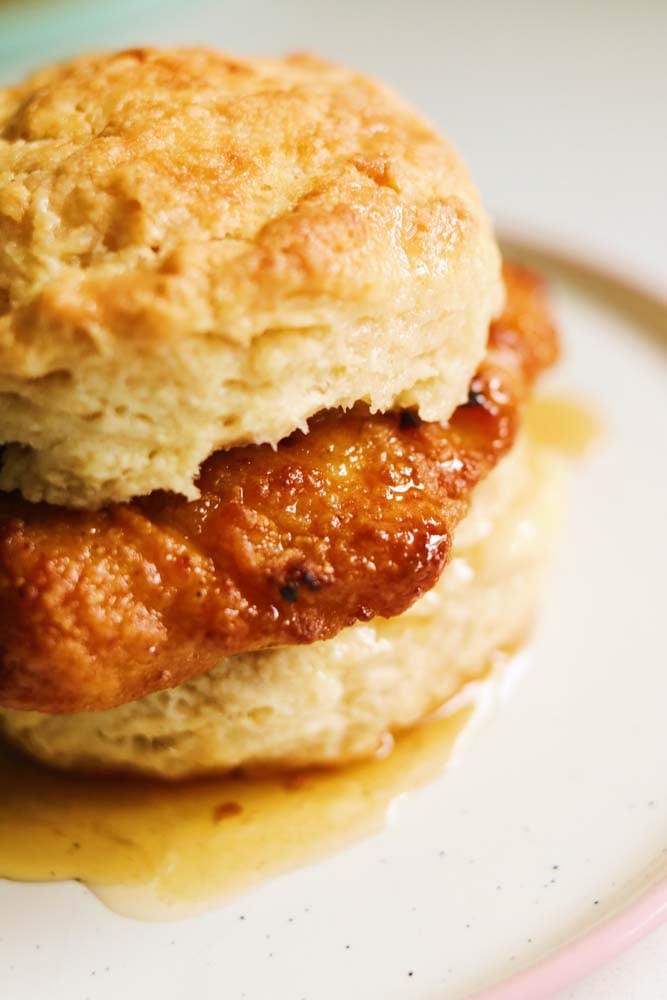 an overhead view of a honey butter chicken biscuit on a white plate. 