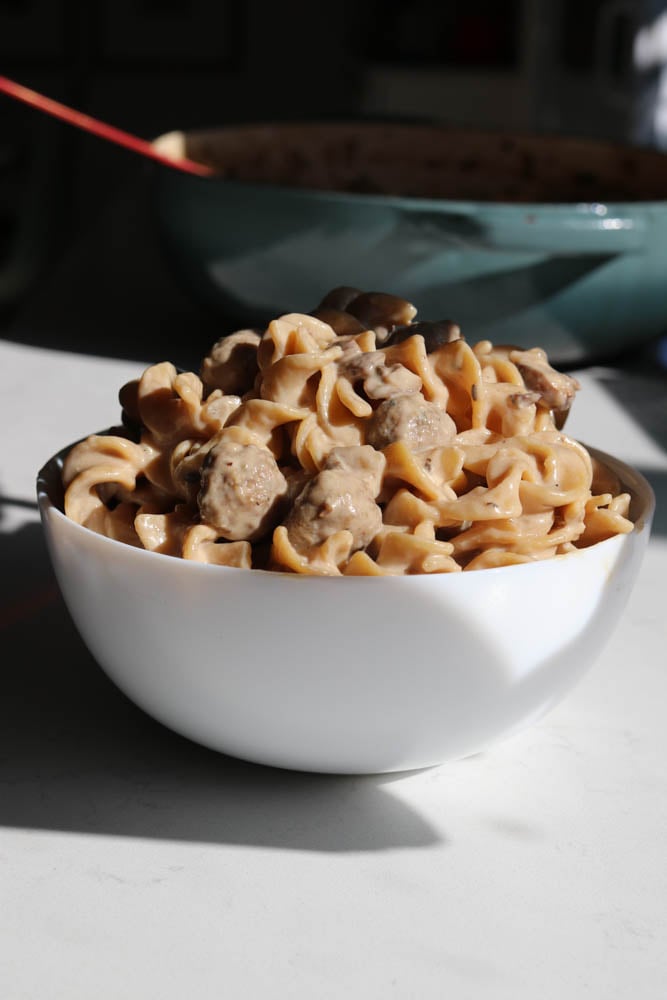 a white serving bowl filled with creamy meatball stroganoff.