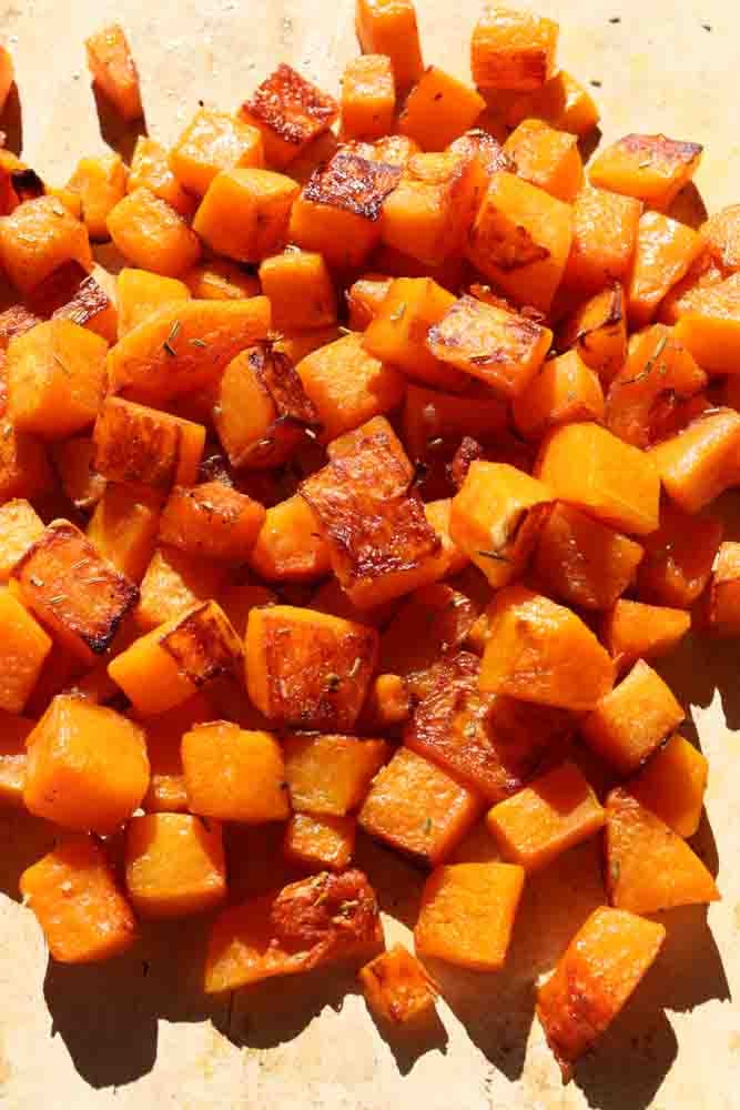 a white baking sheet filled with brown sugar roasted butternut squash., 