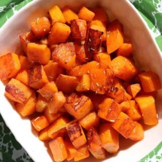 a white bowl filled with bright orange butternut squash cubes.