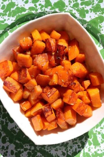 a white bowl filled with bright orange butternut squash cubes.