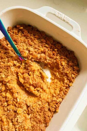 a white baking dish filled with southern candied yams with ritz cracker topping.