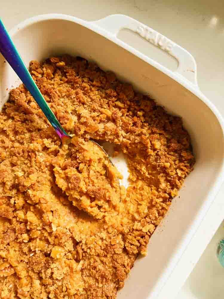 a white baking dish filled with southern candied yams with ritz cracker topping. 