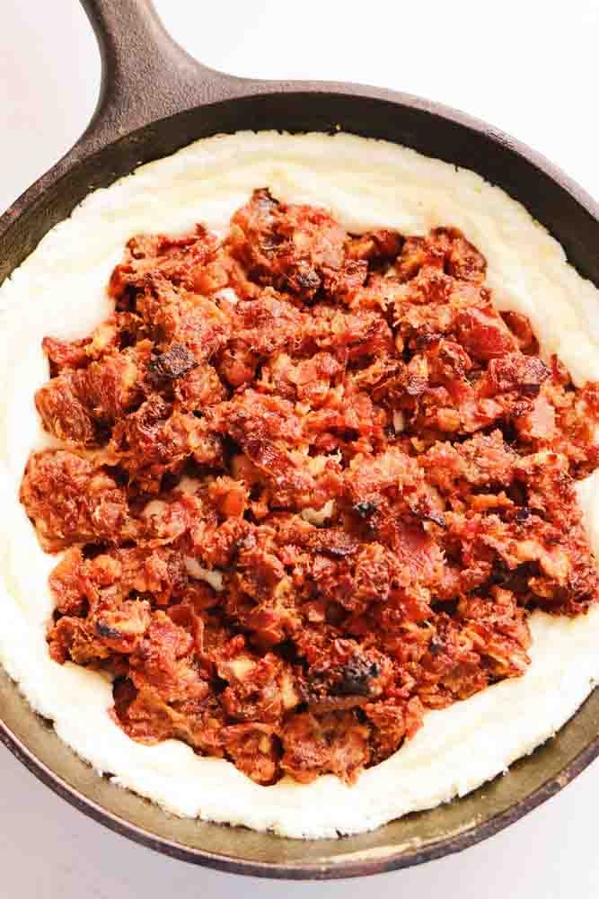 a small black cast iron skillet filled with a sweet and savory white and red dip.