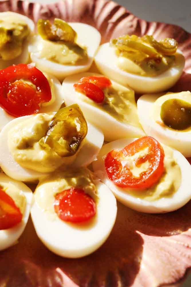 the right side of a pink plate filled with candied jalapeno deviled eggs. 