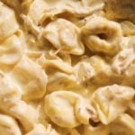 An up close view of chicken tortellini alfredo in a pot.