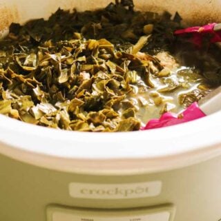 a green slowcooker crockpot filled with tender collard greens.