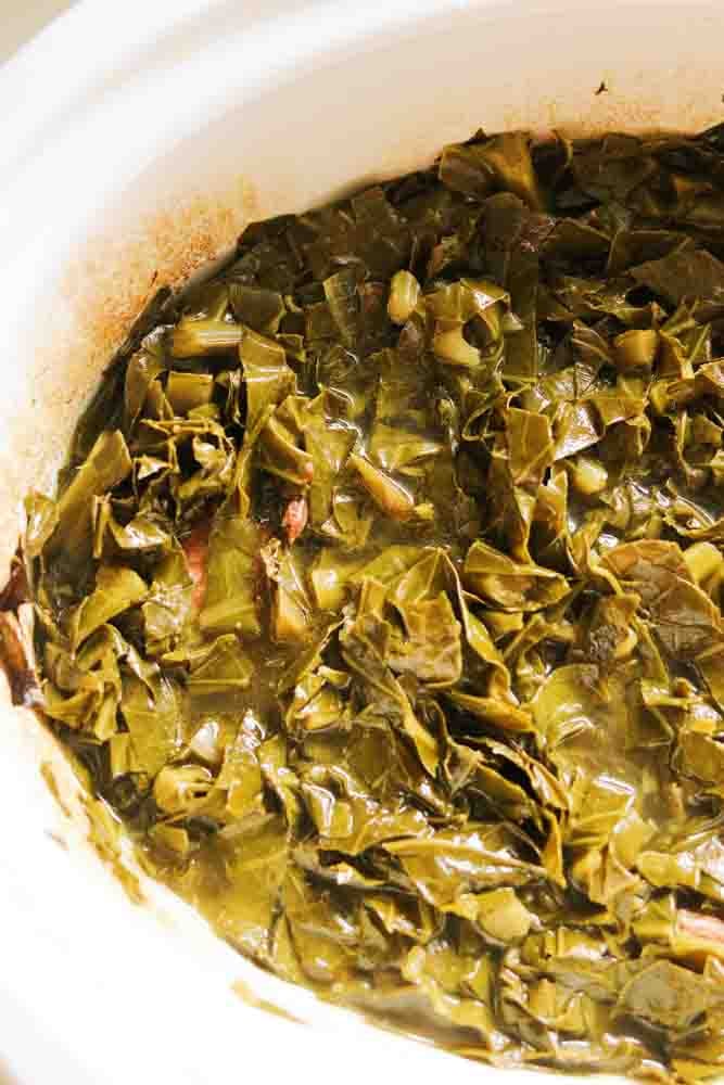 the left side of a slow cooker filled with tender collard greens. 