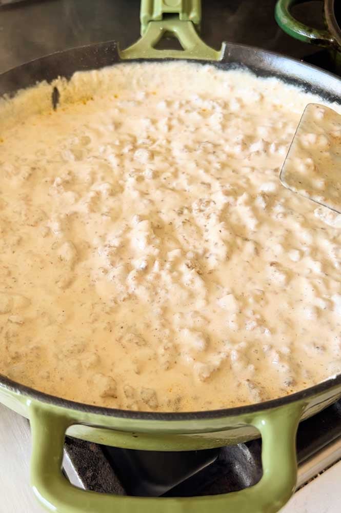 a cast iron skillet full of off white sausage gravy. 