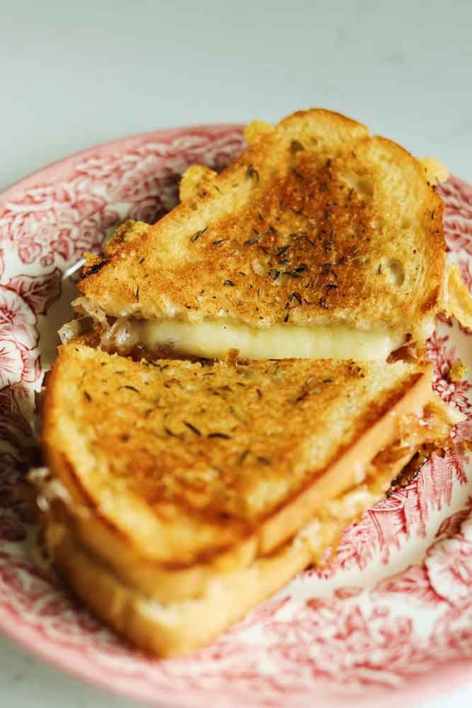 a gruyere grilled cheese split in half on a pink plate. 
