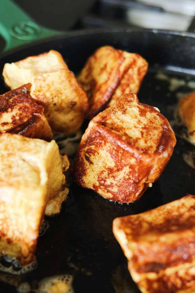 a large fry pan cooking hawaiian roll french toast with lots of salty butter bubbling. 