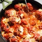 ricotta meatballs swimming in red sauce in a green cast iron skillet.