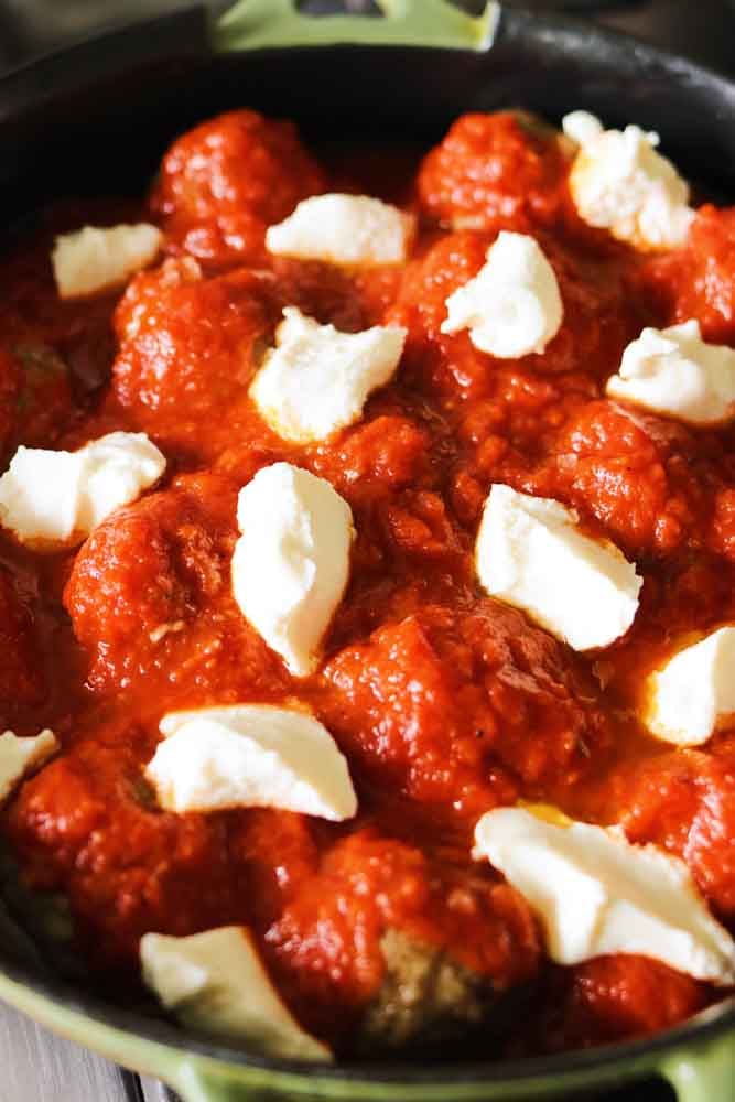 sauce and cheese on top of a batch of ricotta meatballs.