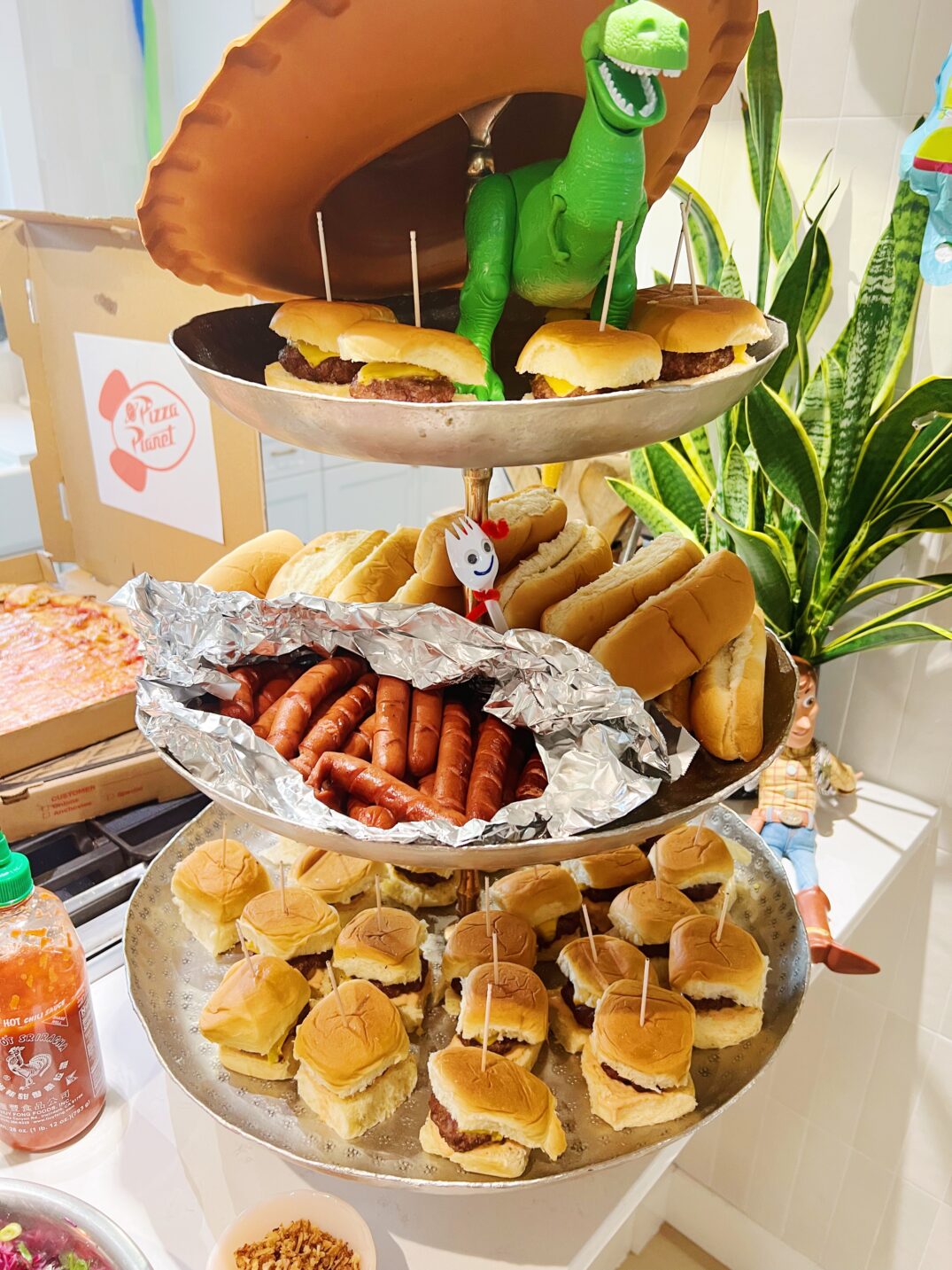 a three tiered platter full of toy story themed burgers and hot dogs