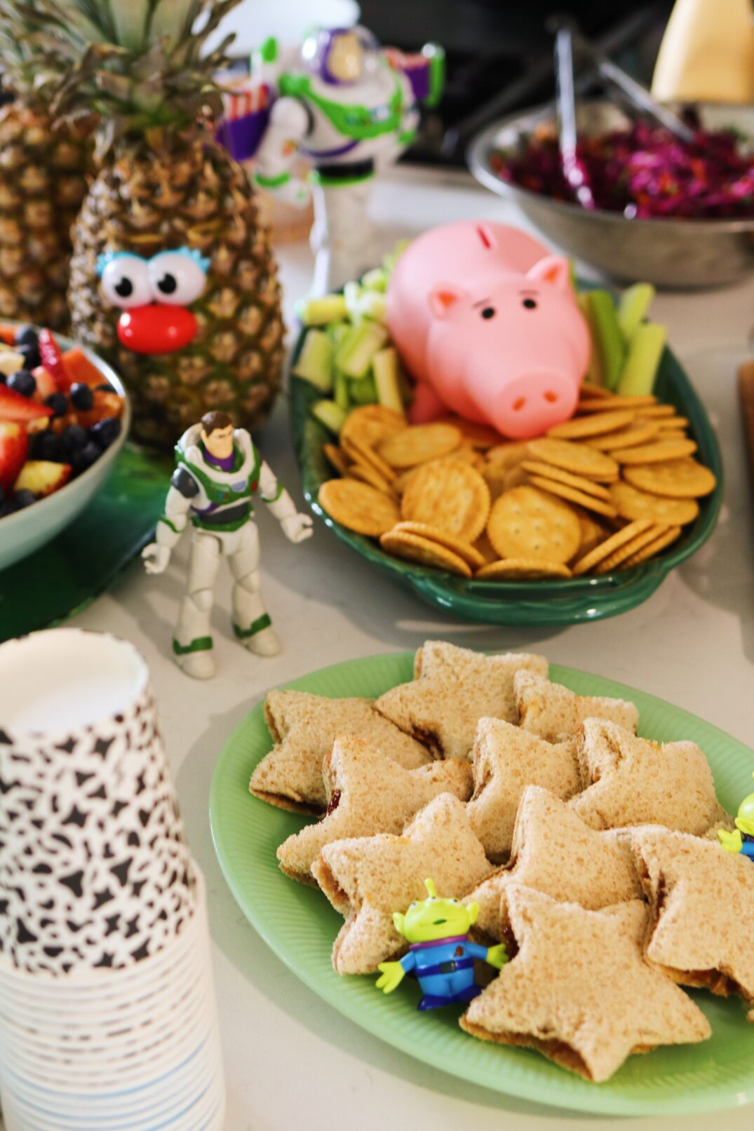 toy story themed food for a birthday party on a white table with toys around it. 
