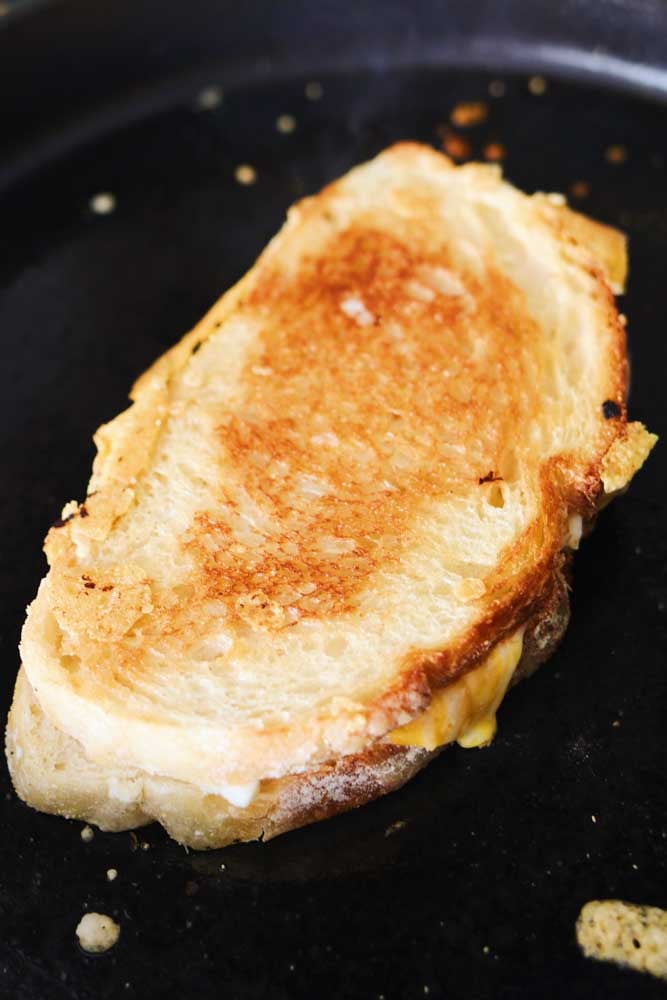 a grilled cheese sandwich cooking in a large cast iron skillet. 