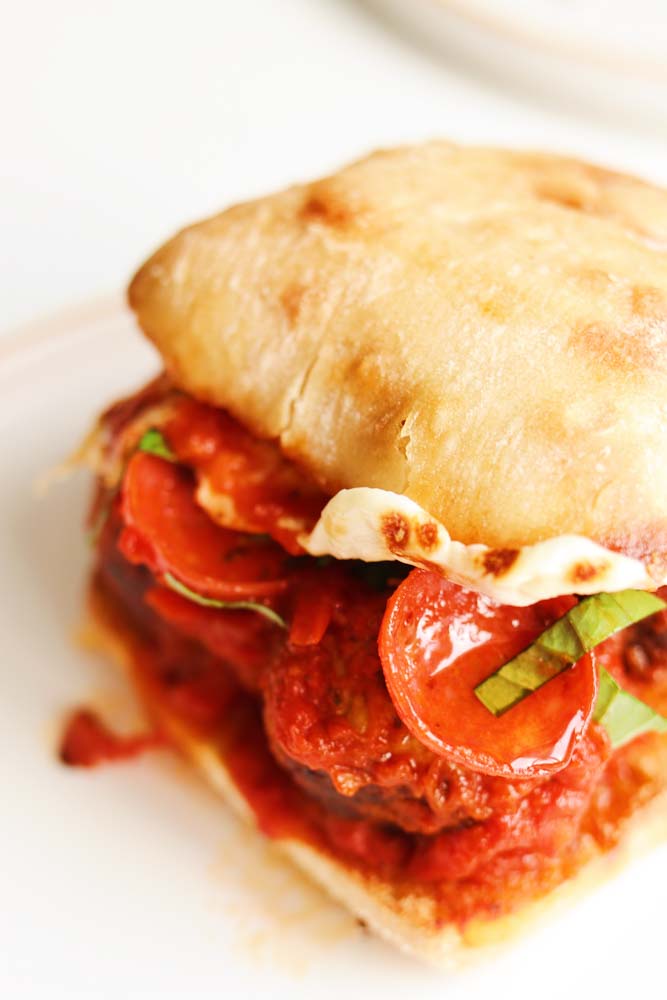 an up close view of a pepperoni pizza inspired meatball sub on a white plate. 