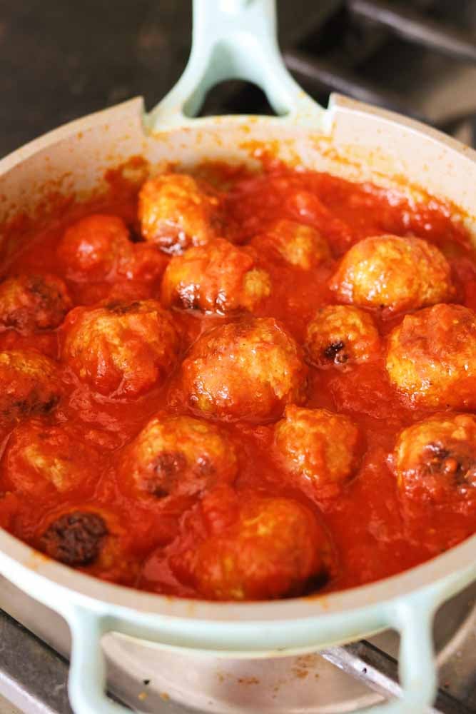 meatballs cooking in sauce in a blue pan.