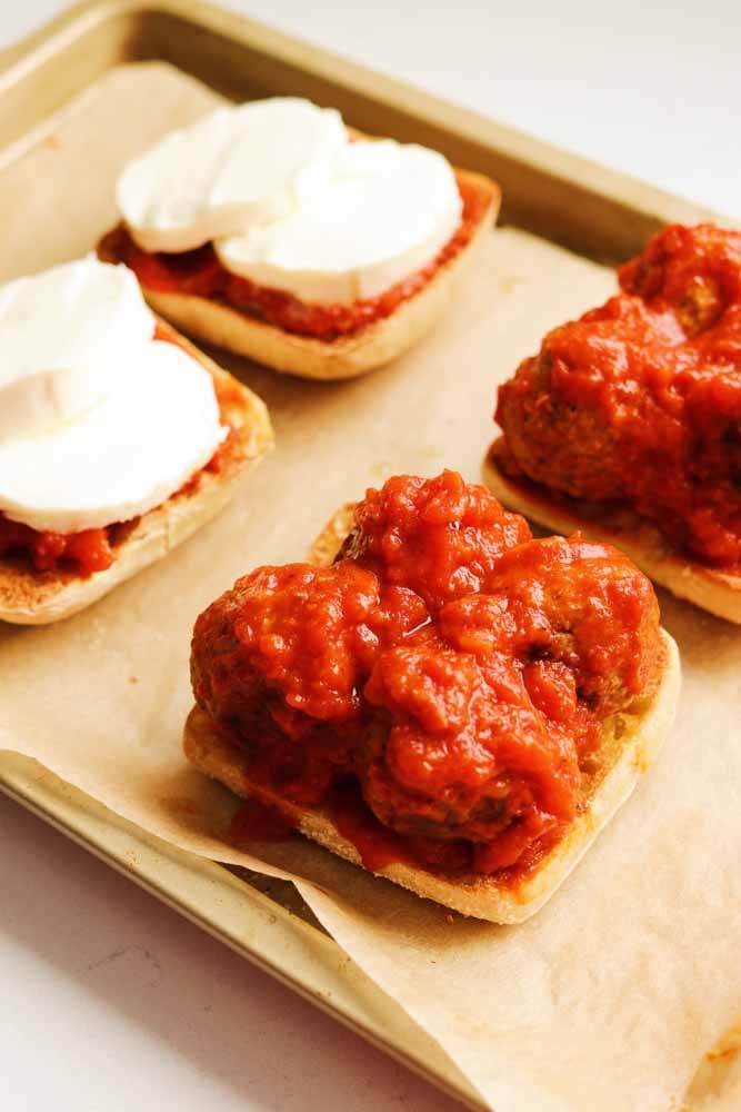an open faced pepperoni pizza meatball sub on a baking sheet. 