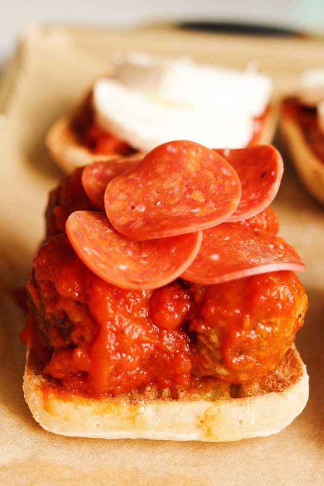 building a meatball sub on a baking sheet with pepperoni on top. 