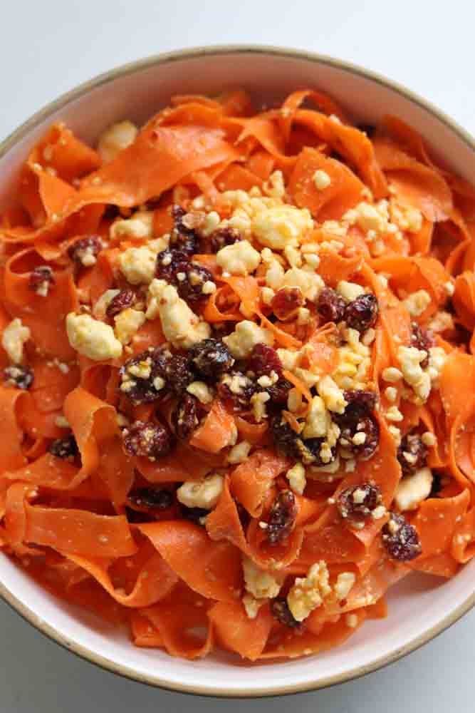 an overhead view of shaved carrot salad in a white bowl. 
