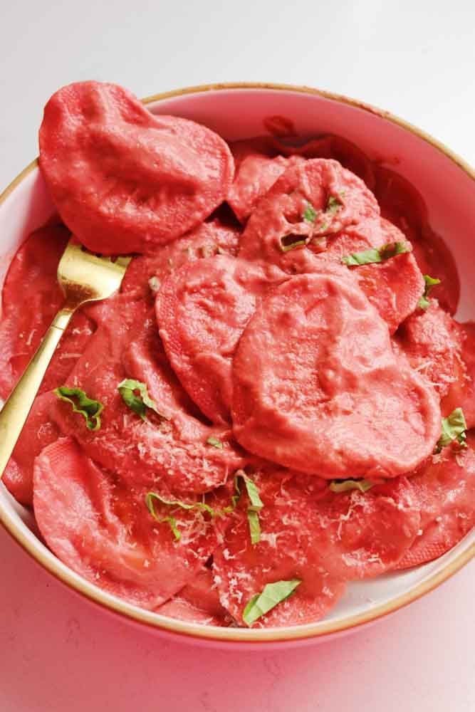 a bowl of pink Trader Joe's Cuoricini Ravioli in a beet goat cheese sauce with a golden fork. 