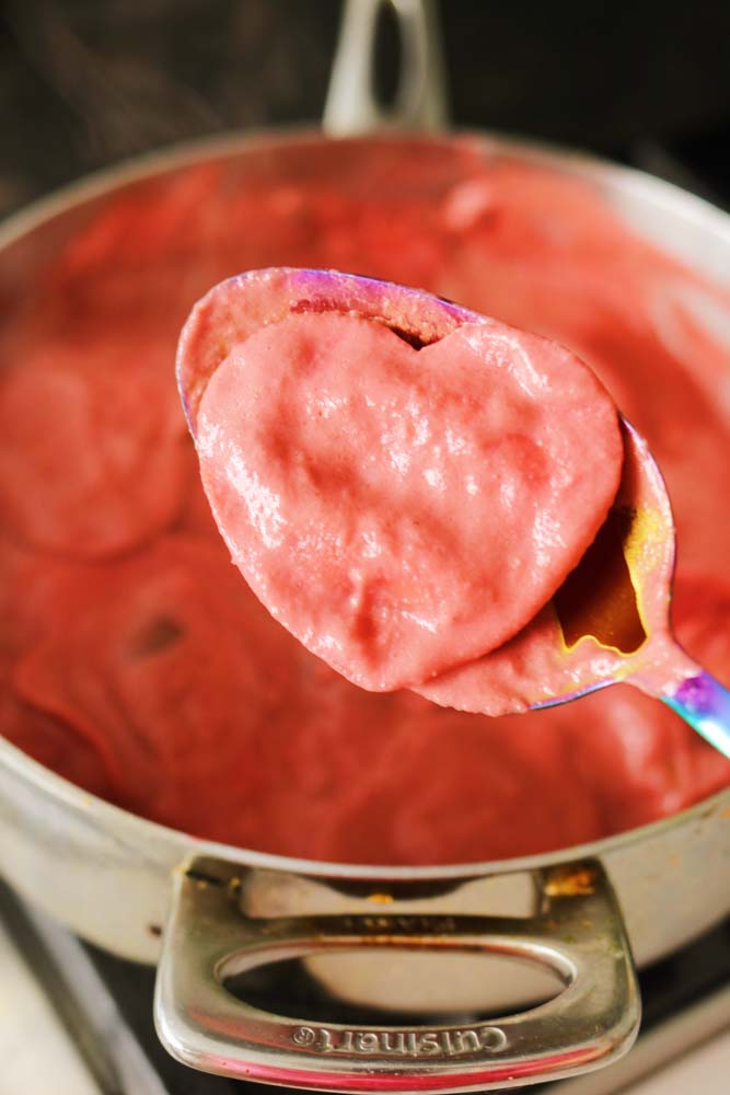 a blue spoon holding a pink sauce heart shaped Trader Joe's Cuoricini Ravioli. 