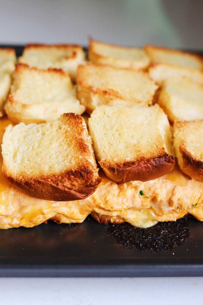 Toasted Hawaiian Rolls baked with buffalo chicken dip in the middle of them on a baking sheet.