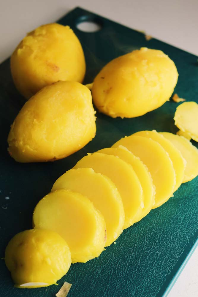 yellow potatoes on a cutting board being sliced into pieces.
