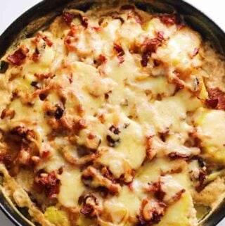 an overhead view of a green cast iron skillet full of french potatoes called tartiflette.