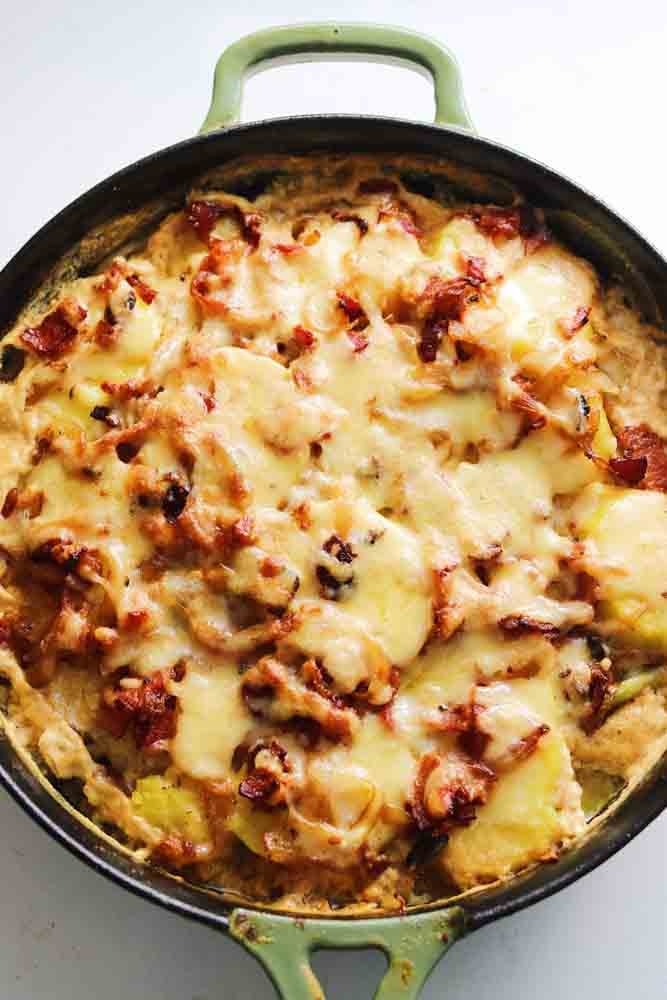 an overhead view of a green cast iron skillet full of french potatoes called tartiflette.