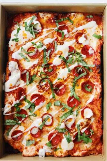 an overhead view of a whole Detroit style pepperoni pizza pie in a metal baking pan.