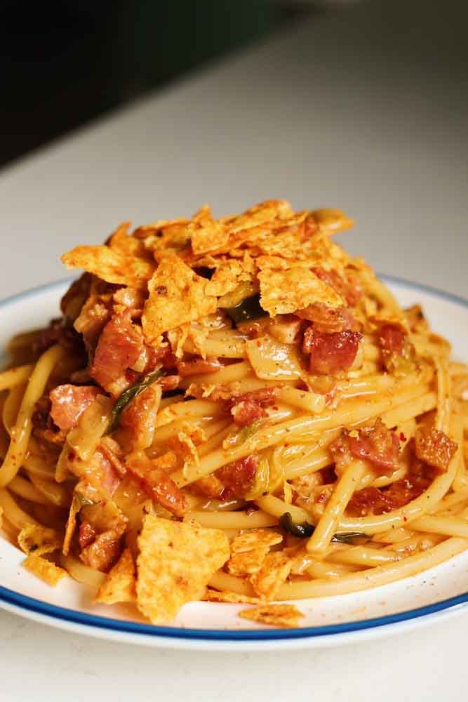 a white plate topped with a swirly pile of kimchi carbonara.