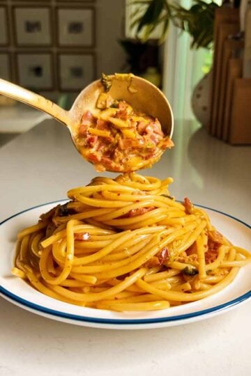 a plate of kimchi carbonara about to be topped with more bacon and kimchi.