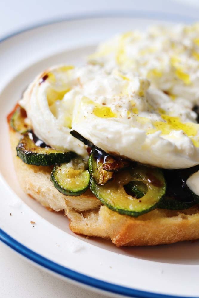 a close up of caramelized zucchini topped with burrata. 