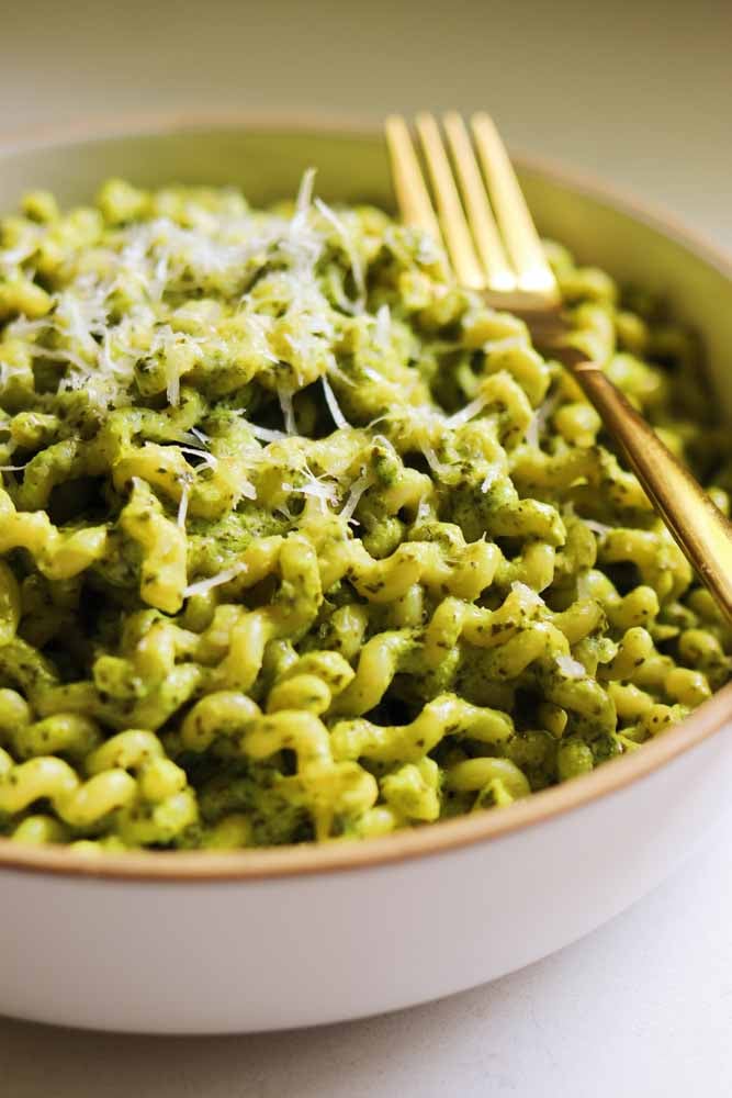 a bowl of pasta tossed in green pasta sauce.