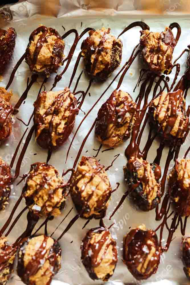an overhead view of stuffed dates with peanut butter on a baking sheet. 