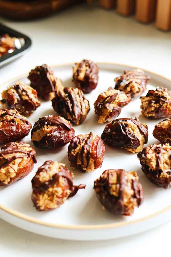 a white plate filled with stuffed dates with peanut butter. 