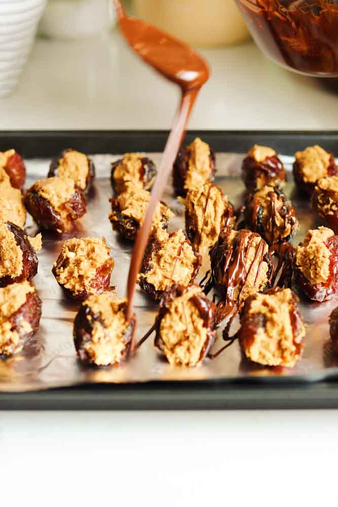 chocolate being drizzled onto peanut butter stuffed dates. 
