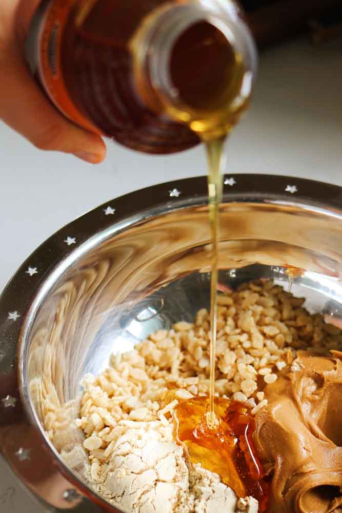 honey being poured into a bowl of ingredients to make protein stuffed dates. 