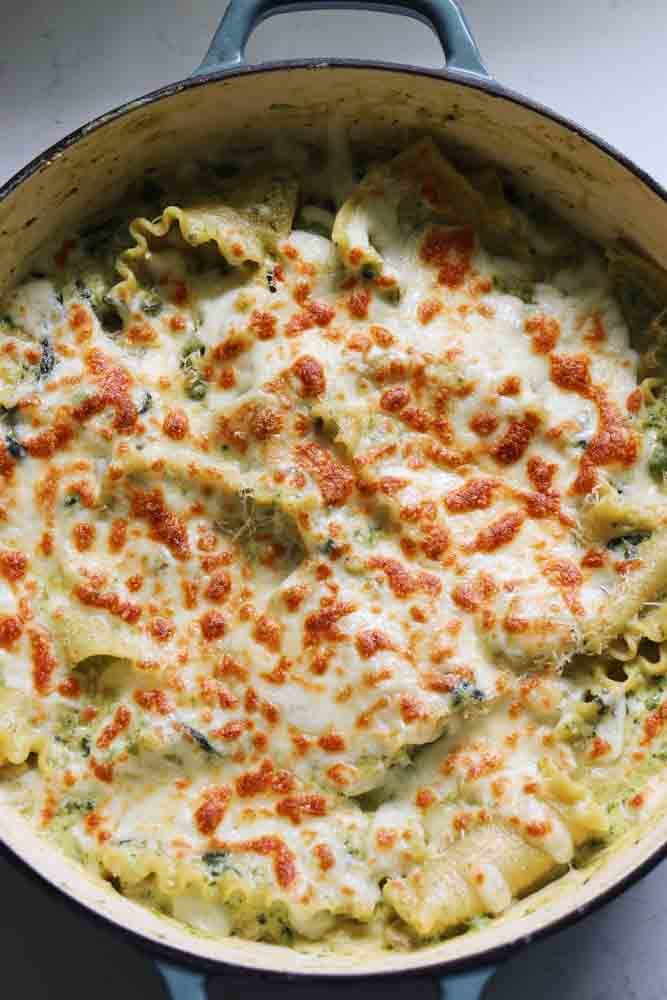 a skillet full of green pesto lasagna with veggies. 