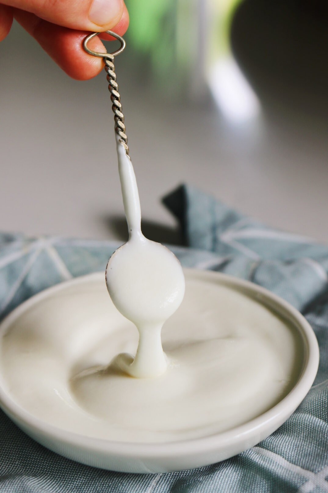 a small silver spoon drizzling cava's garlic sauce over a bowl. 