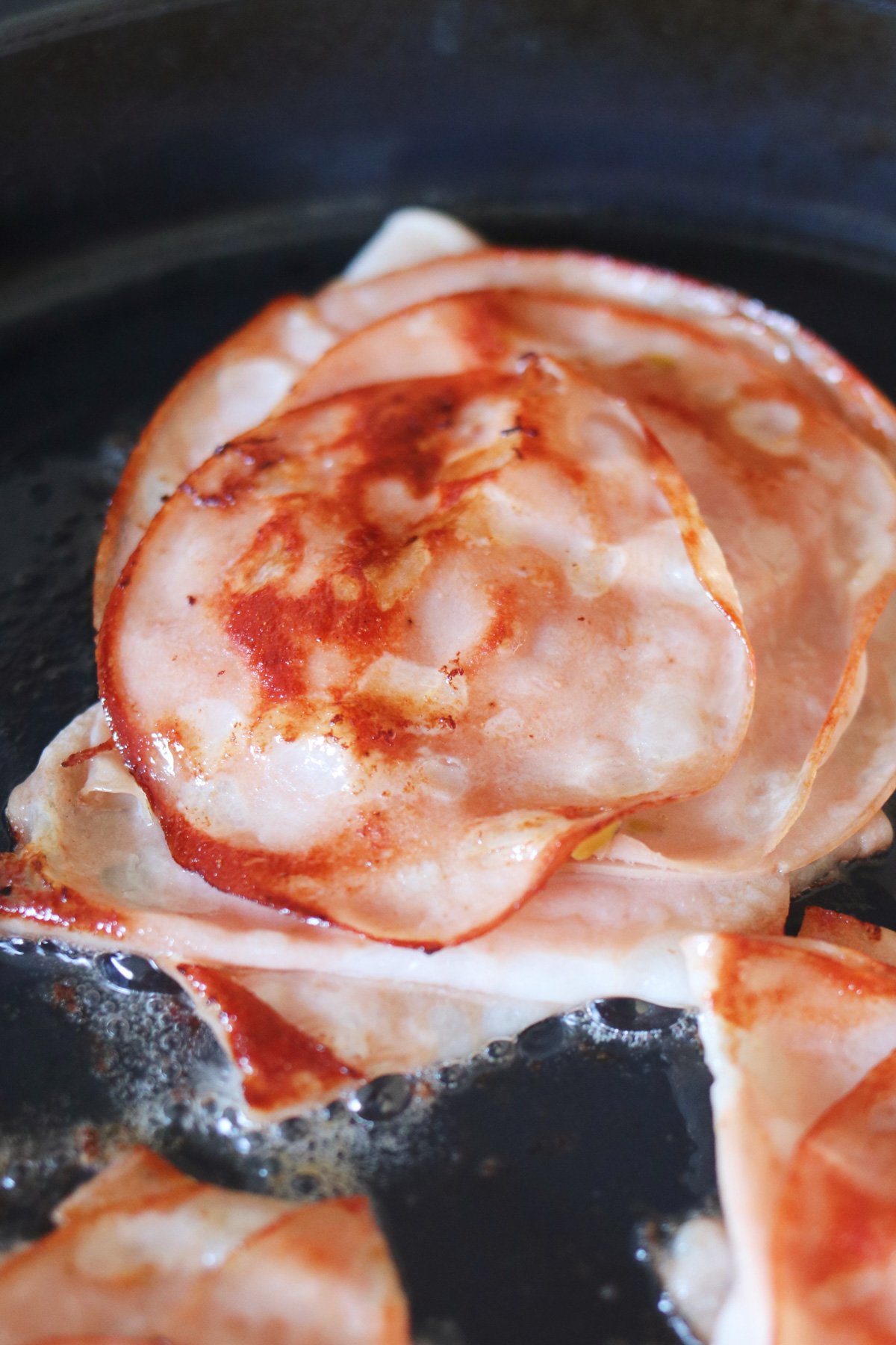 layers of crispy fried mortadella in a frying pan. 