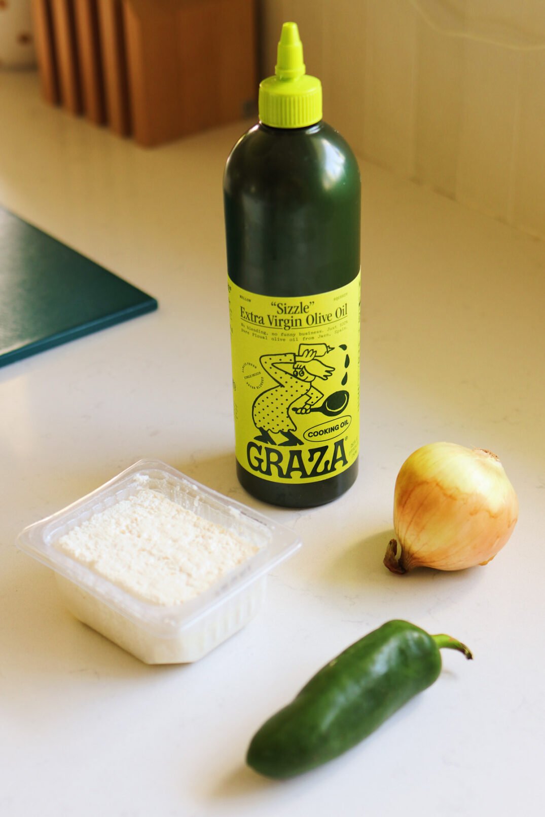 cava crazy feta dip ingredients on a white countertop. Olive oil, feta, jalapeno and onion. 